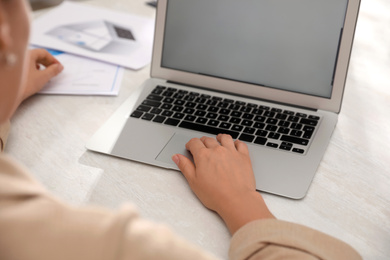 Photo of Woman working with laptop at table in office, closeup