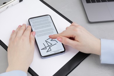 Image of Electronic signature. Woman using mobile phone at table, closeup