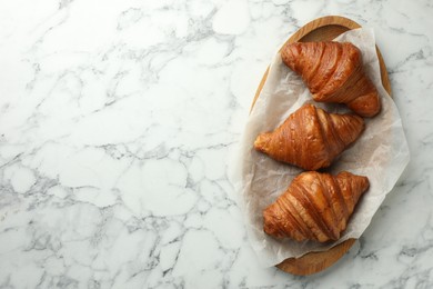 Photo of Tray with tasty croissants on white marble table, top view. Space for text