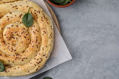 Photo of Delicious puff pastry with spinach on grey table, flat lay. Space for text