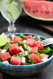 Photo of Delicious salad with watermelon served on black table, closeup