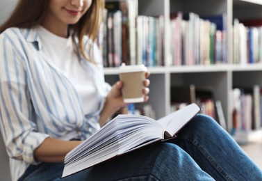 Photo of Young woman with book on floor in library, closeup