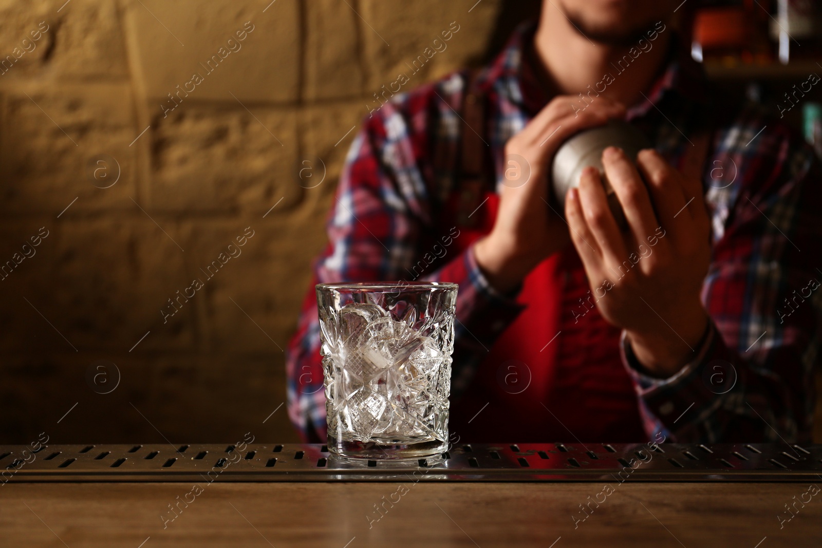 Photo of Bartender preparing fresh alcoholic cocktail at bar counter, focus on glass