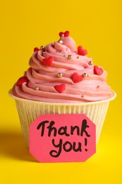 Photo of Tasty cupcake and note with phrase Thank You on yellow background