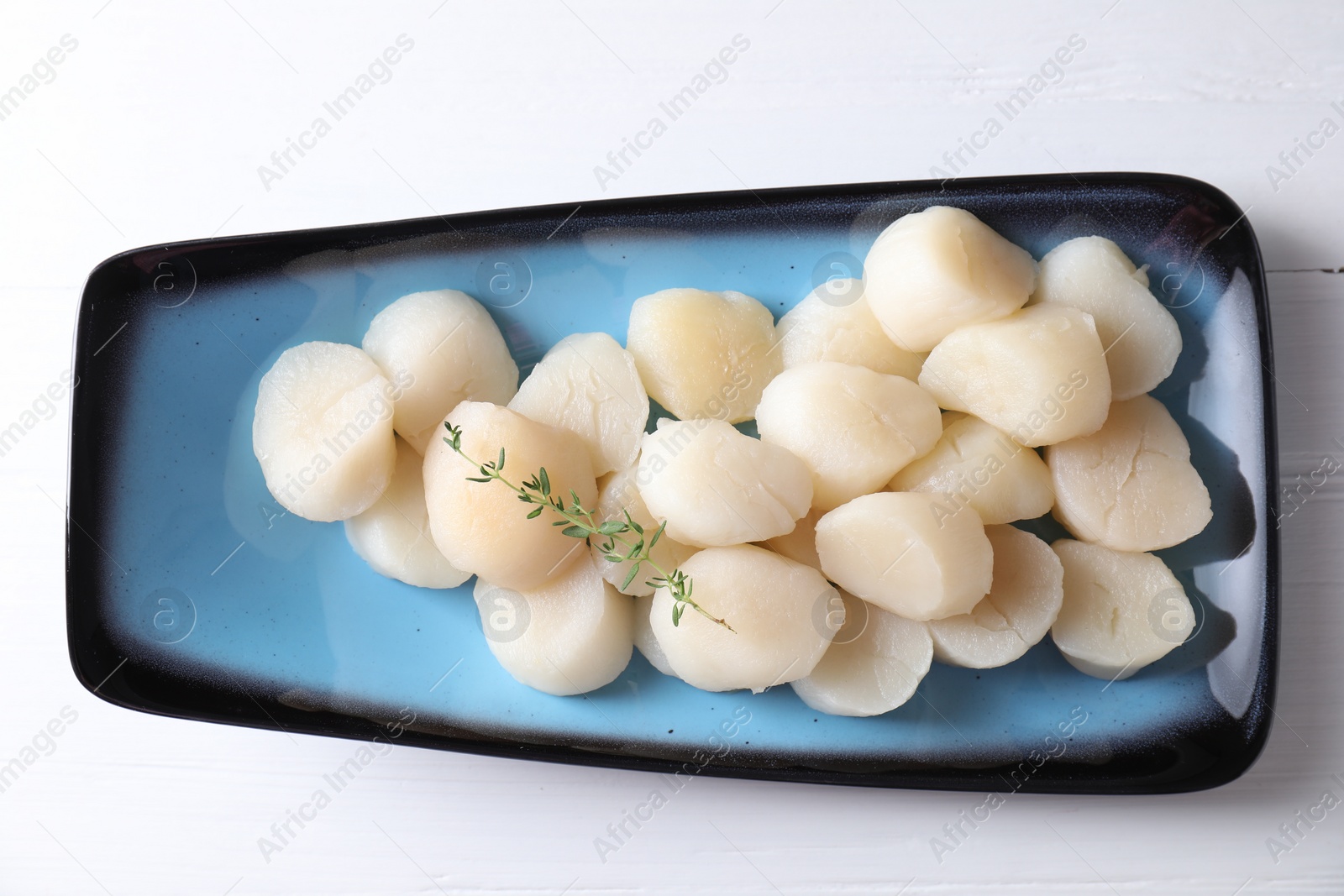 Photo of Fresh raw scallops and thyme on white wooden table, top view