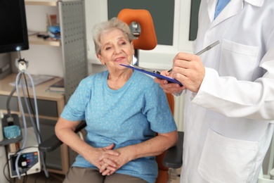 Photo of Senior woman visiting otolaryngologist in clinic. Hearing aid