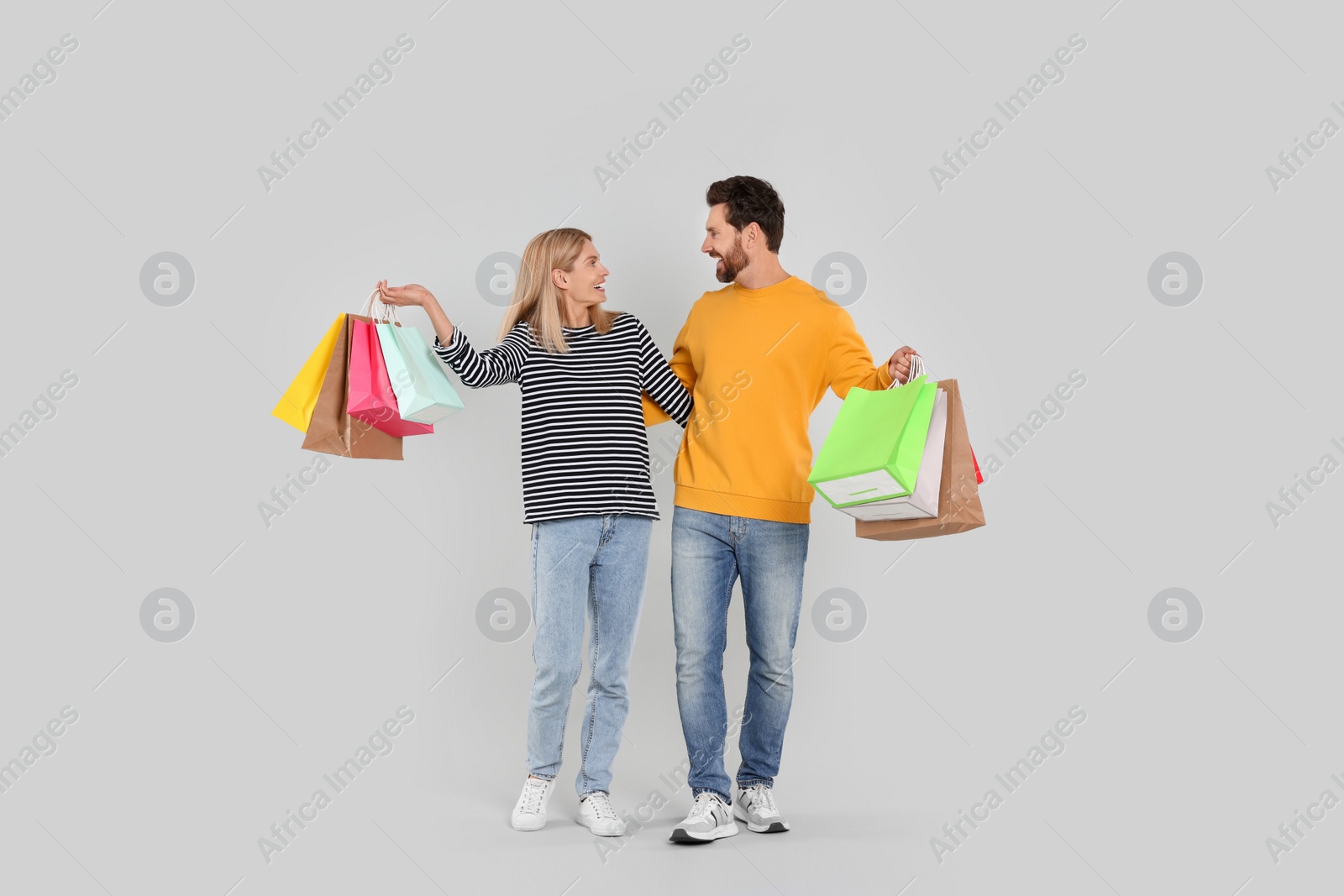 Photo of Family shopping. Happy couple with many colorful bags on light grey background