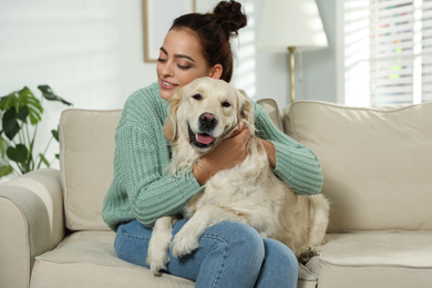 Photo of Young woman and her Golden Retriever on sofa at home. Adorable pet
