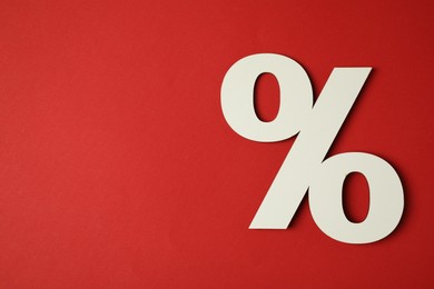 Photo of White percent sign on red background, top view. Space for text