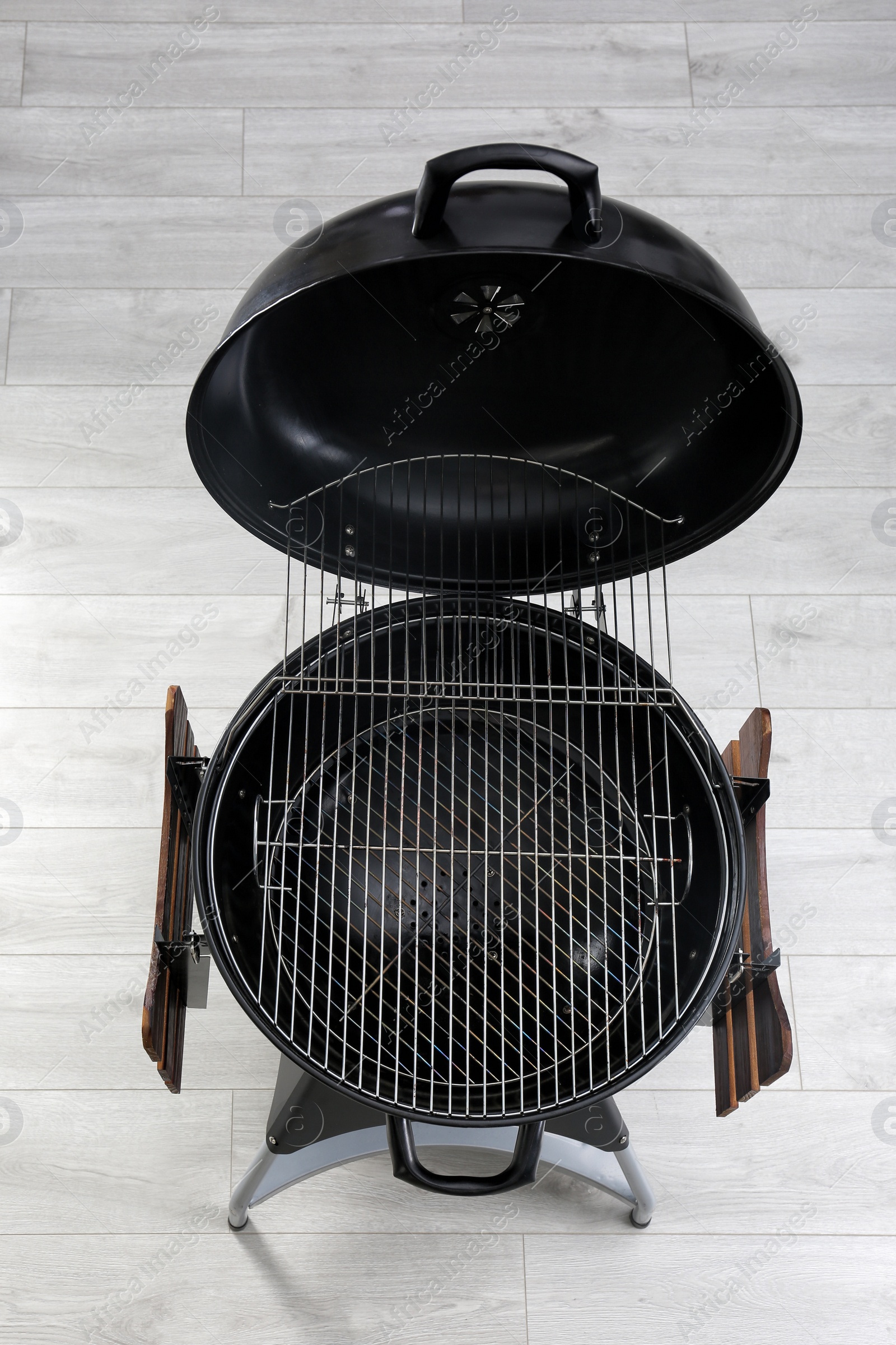 Photo of New modern barbecue grill on wooden floor