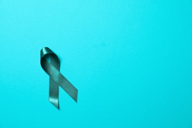 Teal awareness ribbon on light blue background, top view with space for text. Symbol of social and medical issues