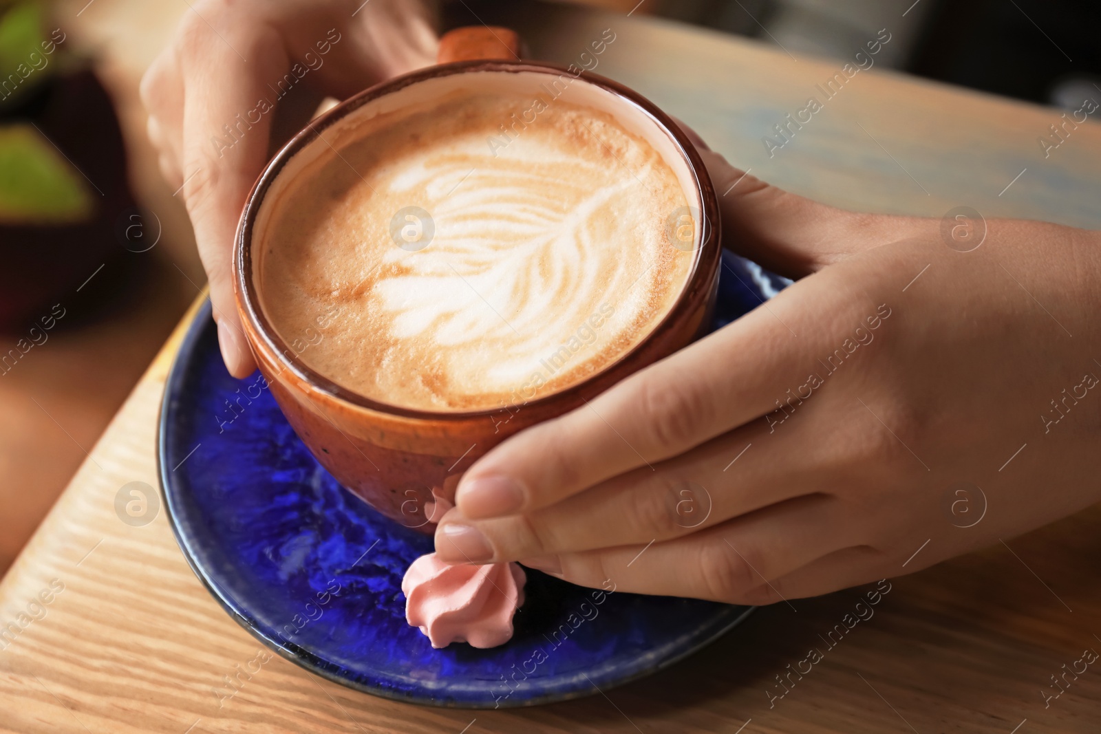Photo of Woman with cup of aromatic coffee with foam at wooden table