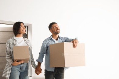 Photo of Happy couple with moving boxes entering in new apartment