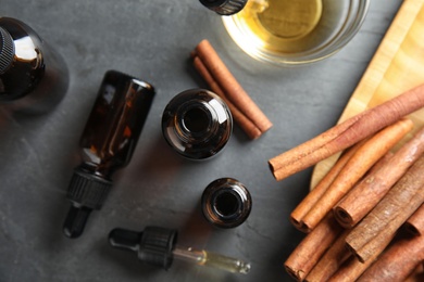 Photo of Composition with cinnamon essential oil on grey table, flat lay