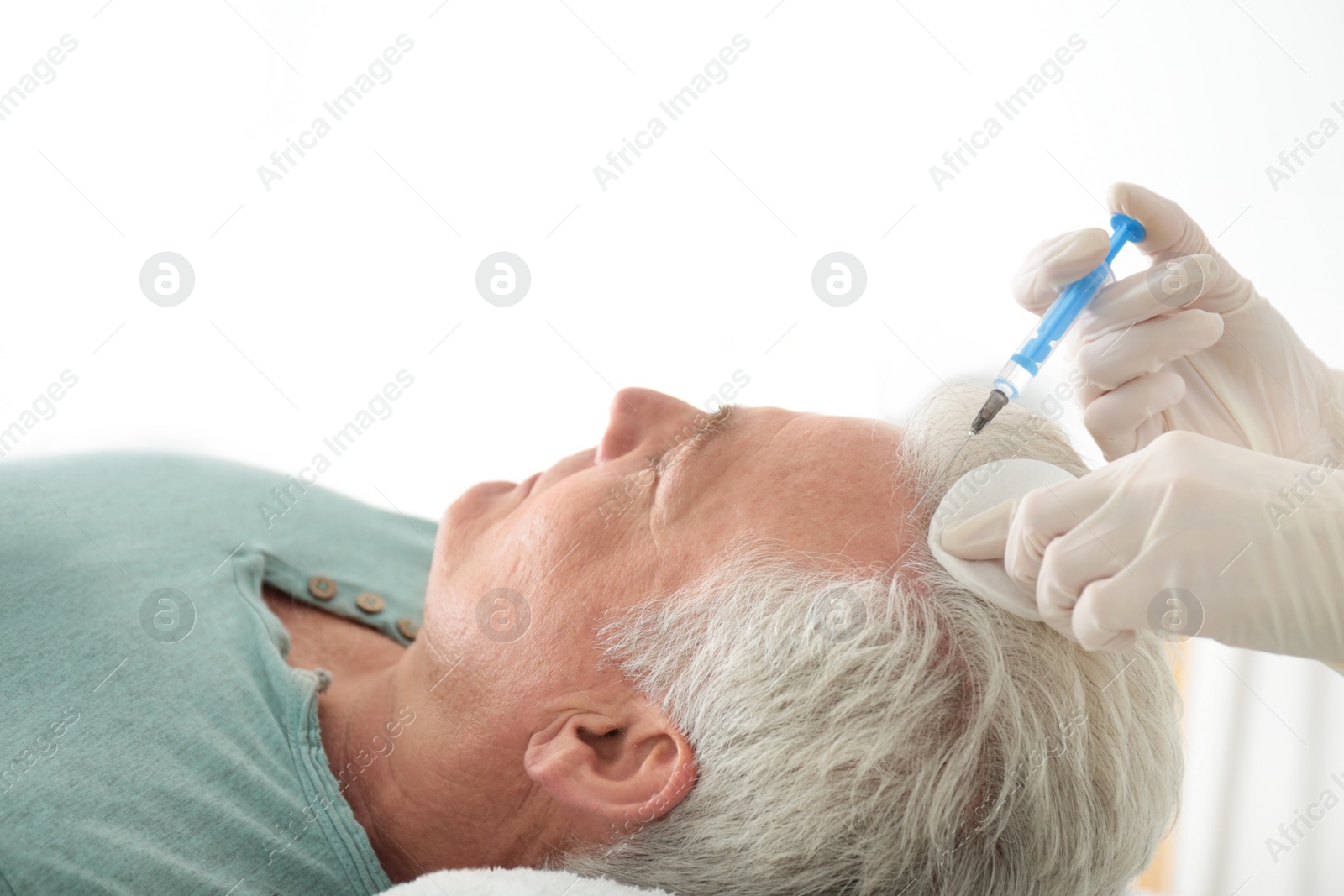 Photo of Senior man with hair loss problem receiving injection in salon