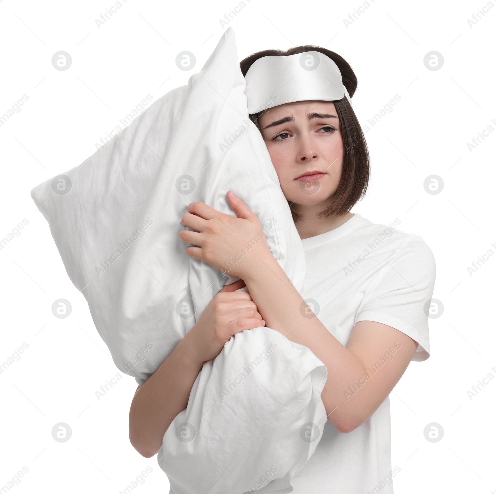 Photo of Unhappy young woman with sleep mask and pillow on white background. Insomnia problem
