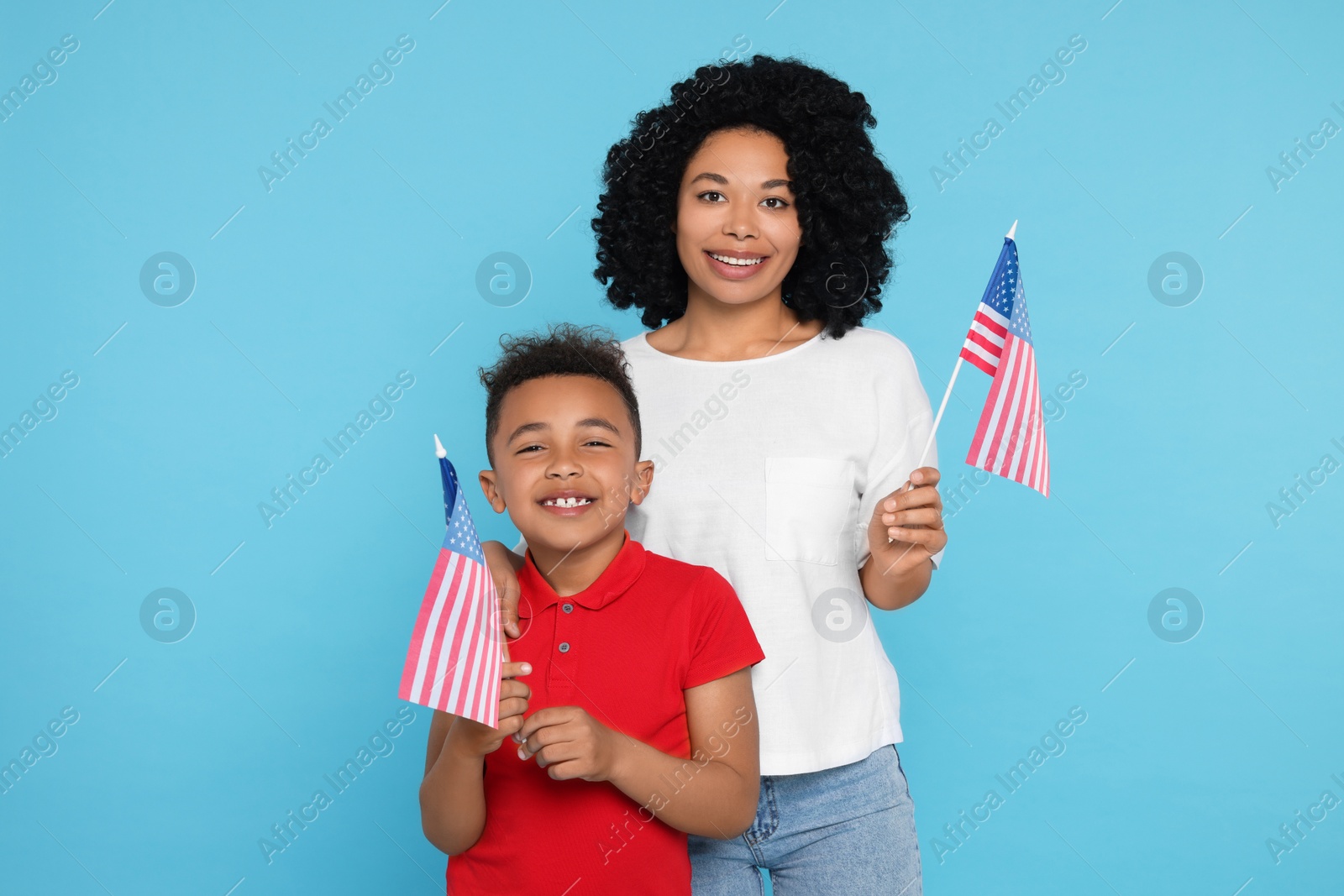 Photo of 4th of July - Independence Day of USA. Happy woman and her son with American flags on light blue background