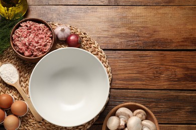 Bowl and different products on wooden table, flat lay. Space for text