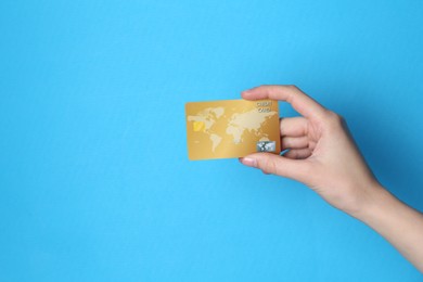 Photo of Woman holding credit card on light blue background, closeup