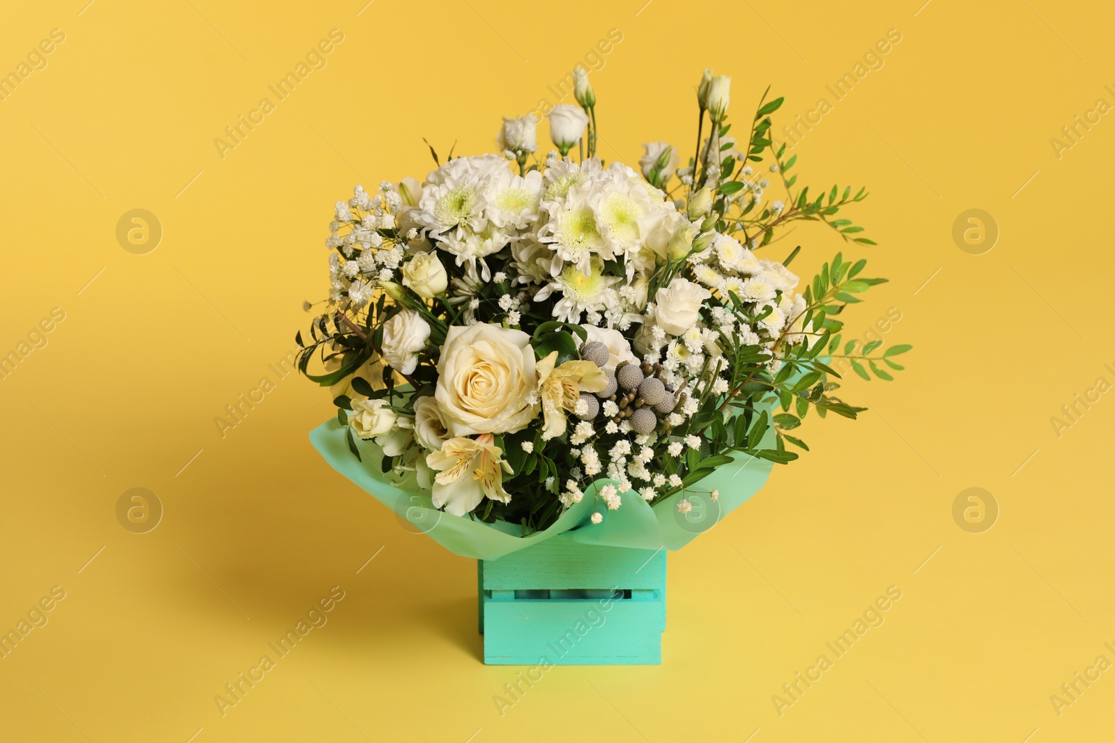 Photo of Beautiful bouquet of flowers in decorative crate on color background