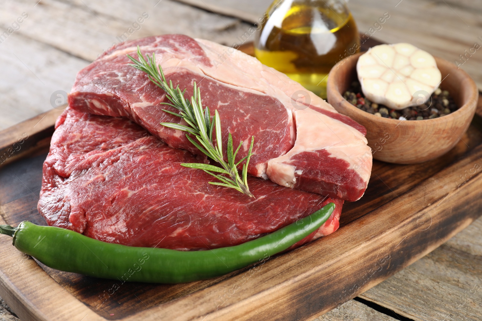 Photo of Fresh raw beef cut with spices on wooden table, closeup