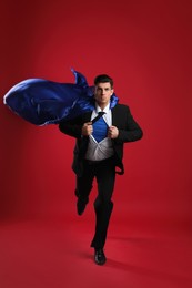 Photo of Man wearing superhero cape on red background