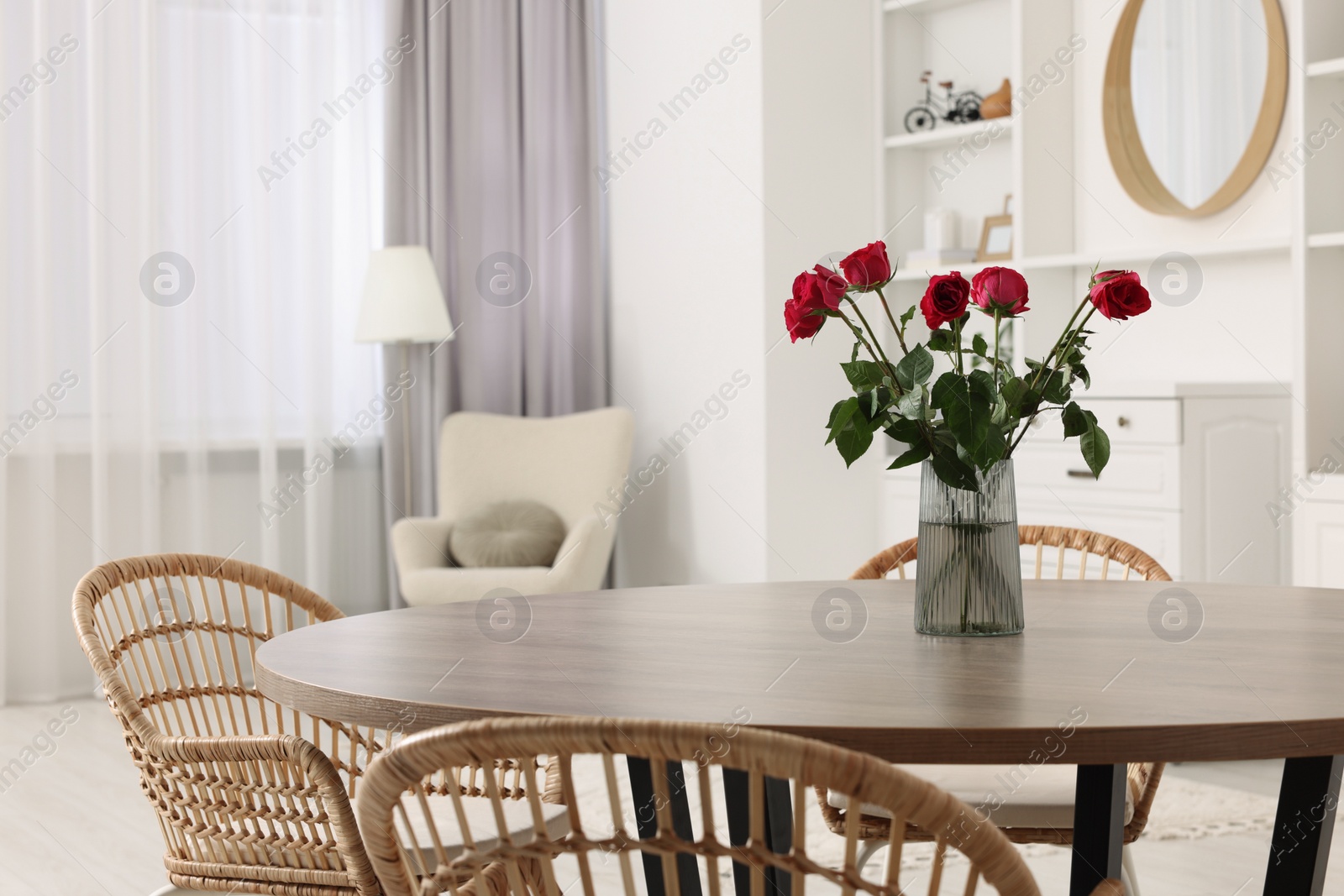 Photo of Chairs and table with vase of red rose flowers in dining room. Stylish interior