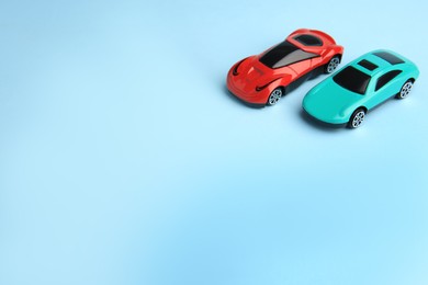 Photo of Two bright cars on light blue background, space for text. Children`s toys