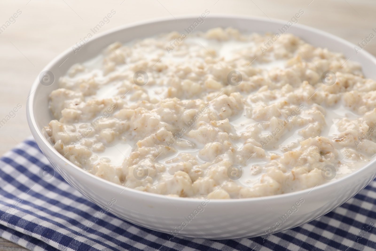 Photo of Tasty boiled oatmeal in bowl on table, closeup