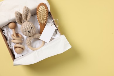 Photo of Different baby accessories and blank card in box on yellow background, top view. Space for text