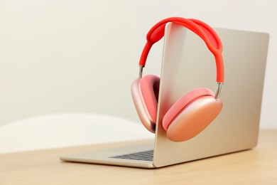 Modern laptop and headphones on wooden table. Space for text