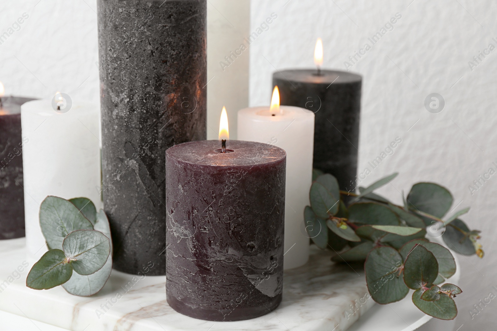 Photo of Burning candles and green branches on table