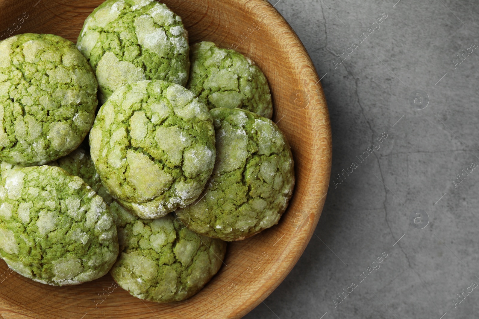 Photo of Bowl with tasty matcha cookies on grey textured table, top view. Space for text