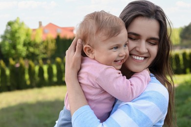 Happy mother with her cute baby at backyard on sunny day