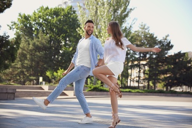 Photo of Lovely young couple dancing together outdoors on sunny day