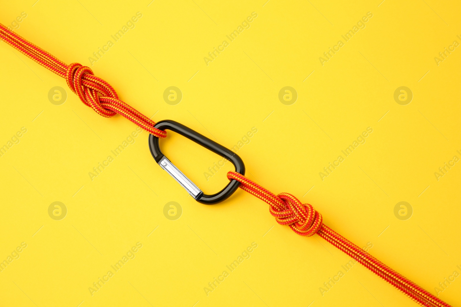 Photo of One metal carabiner with ropes on yellow background, top view