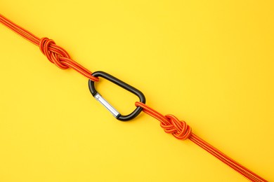 One metal carabiner with ropes on yellow background, top view