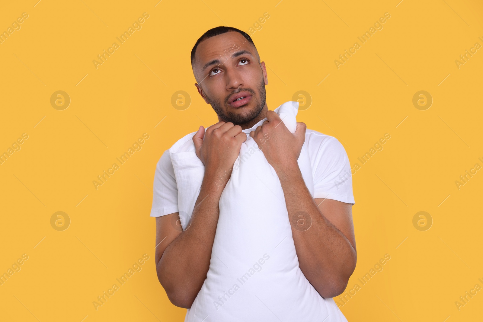 Photo of Tired man with pillow on orange background. Insomnia problem