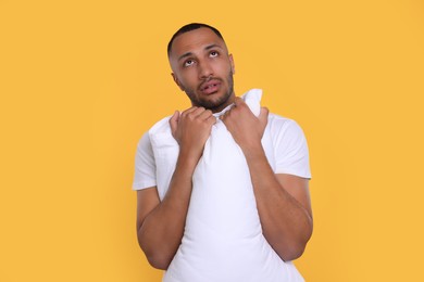 Photo of Tired man with pillow on orange background. Insomnia problem