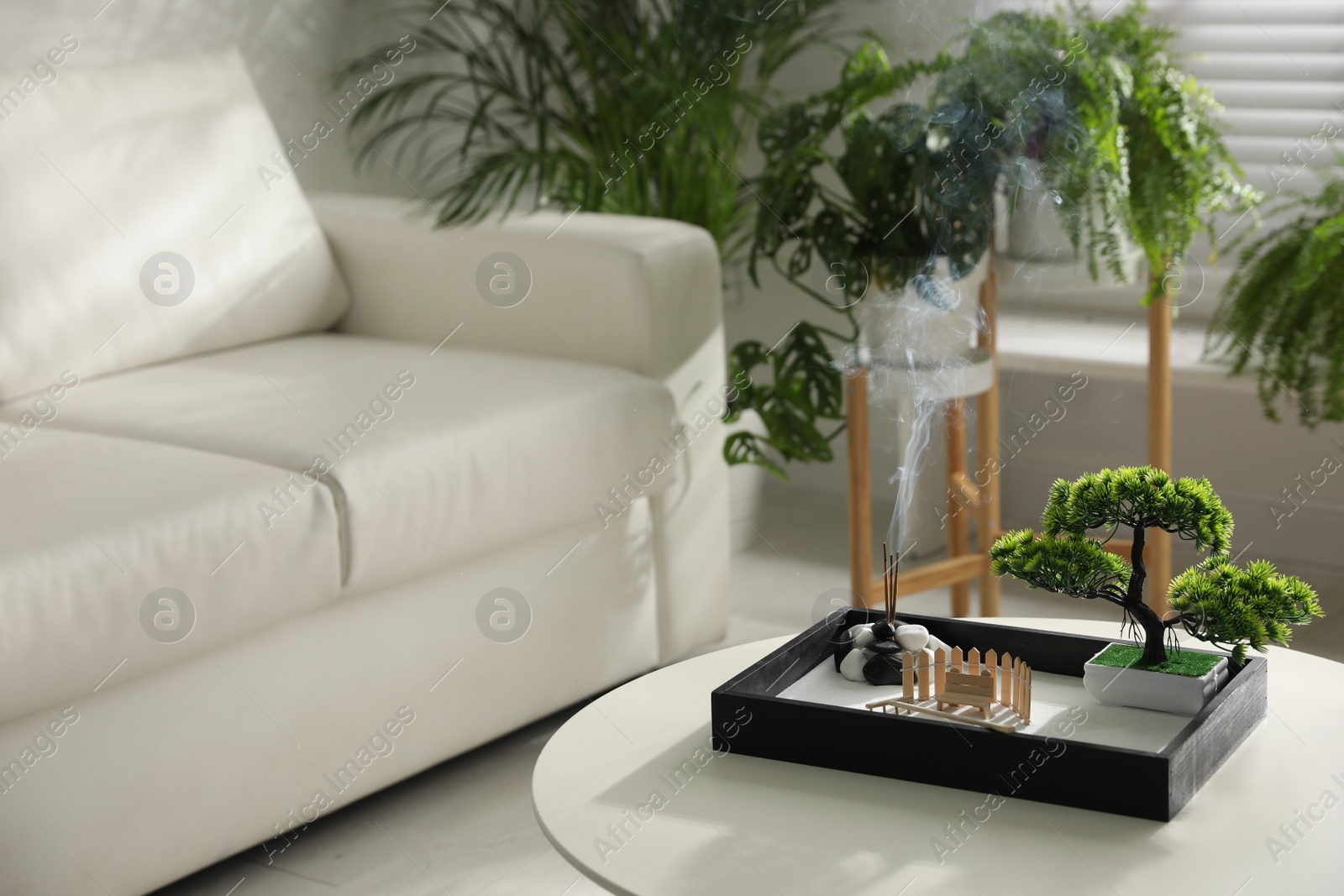 Photo of Beautiful miniature zen garden with incense sticks on table indoors