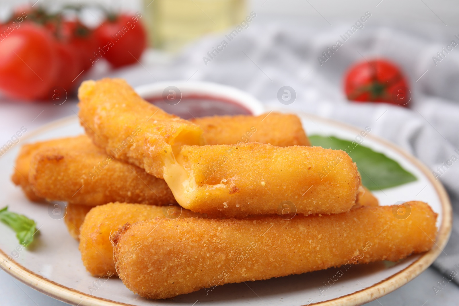 Photo of Tasty fried mozzarella sticks on white table, closeup