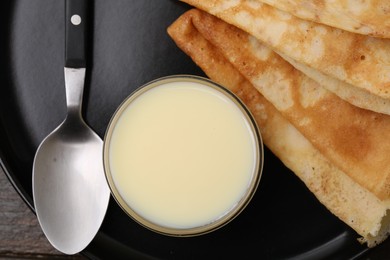 Photo of Tasty condensed milk and crepes on plate, top view