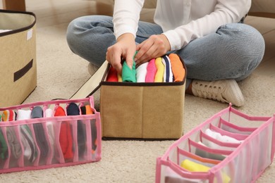 Woman folding clothes on floor at home, closeup. Japanese storage system