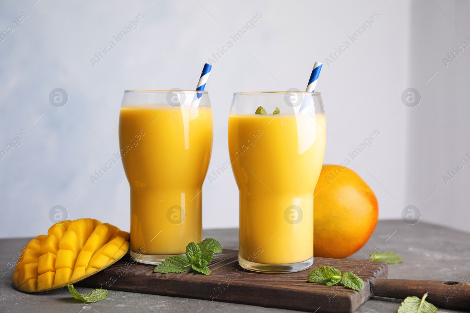 Photo of Glasses of fresh mango drink and fruits on table