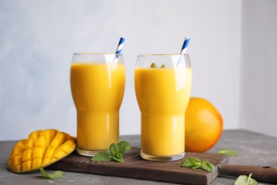 Glasses of fresh mango drink and fruits on table