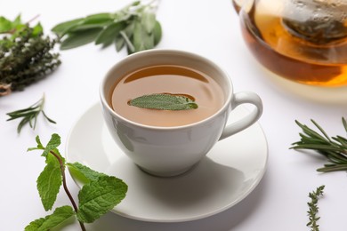 Photo of Aromatic herbal tea with thyme, rosemary, mint and sage on white table