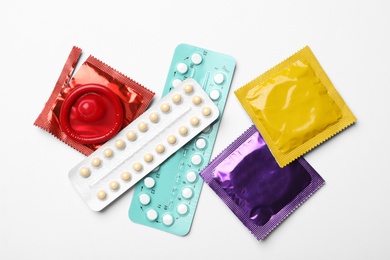 Photo of Condoms and birth control pills on white background, top view. Safe sex concept
