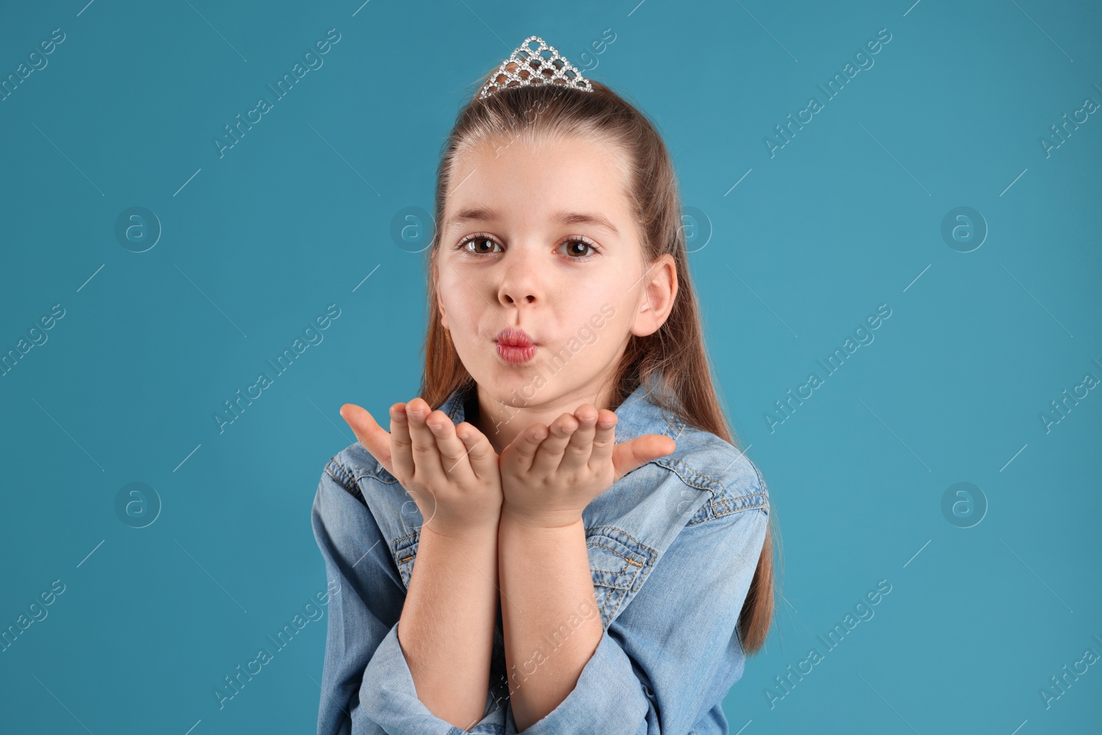 Photo of Cute girl in diadem on light blue background. Little princess