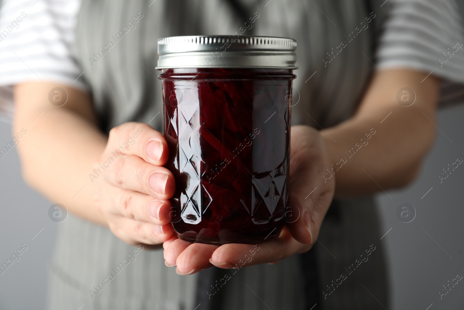 Photo of Woman holding glass jar with pickled beets, closeup