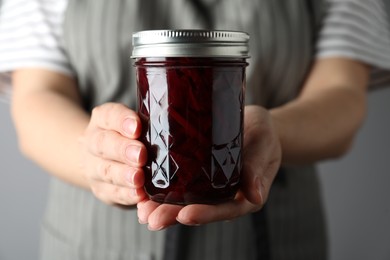 Photo of Woman holding glass jar with pickled beets, closeup